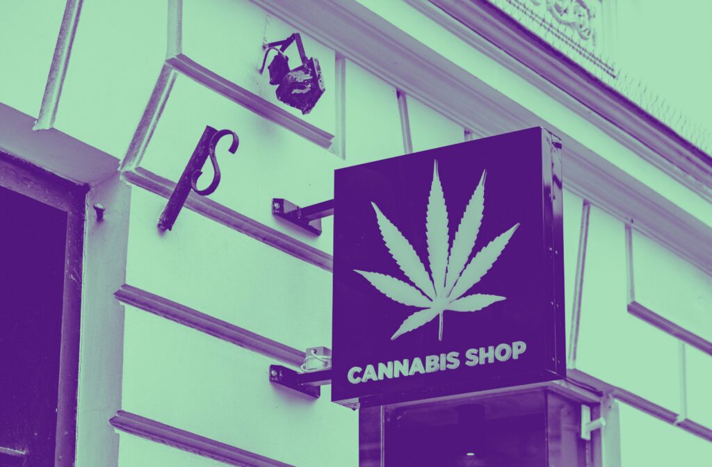 Cannabis dispensary storefront with cannabis leaf sign representing mergers and acquisitions in the cannabis industry.